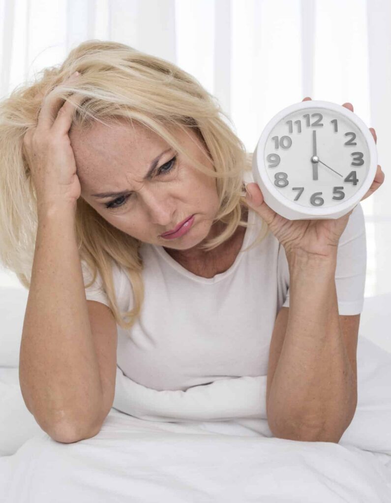 femme fatigué tenant un réveil dans sa main